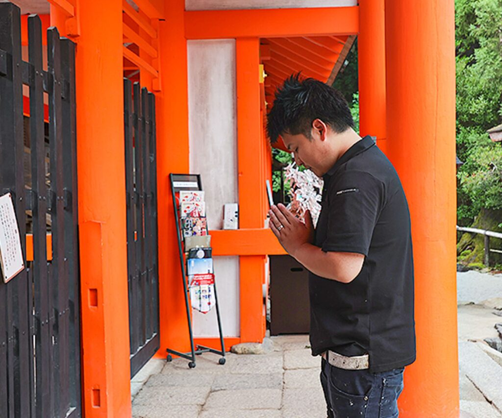 神社にてお祈りを捧げている男性の画像